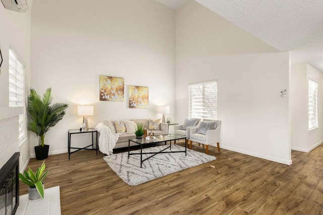 living room featuring a brick fireplace, dark hardwood / wood-style floors, a wall mounted AC, and high vaulted ceiling