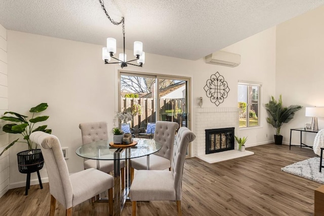 dining area with dark wood-type flooring, a wall mounted AC, a textured ceiling, and a fireplace