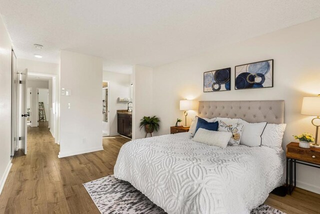 bedroom with connected bathroom and hardwood / wood-style floors