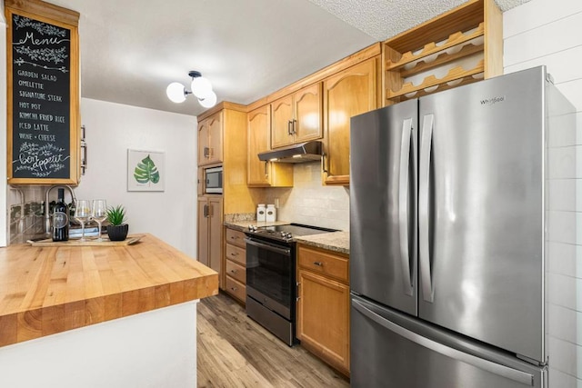 kitchen featuring stainless steel appliances, light stone countertops, light hardwood / wood-style floors, and backsplash