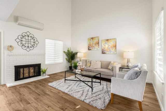 living room featuring a brick fireplace, plenty of natural light, hardwood / wood-style floors, and a wall unit AC