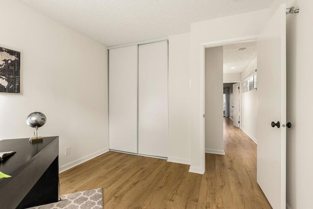 bedroom with a closet, a textured ceiling, and light wood-type flooring