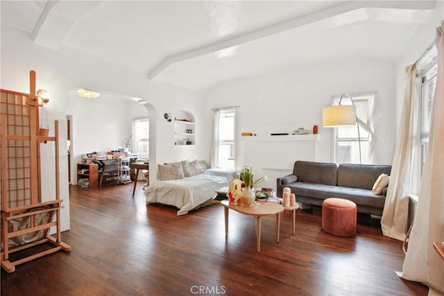 living room with built in shelves, dark wood-type flooring, and beamed ceiling