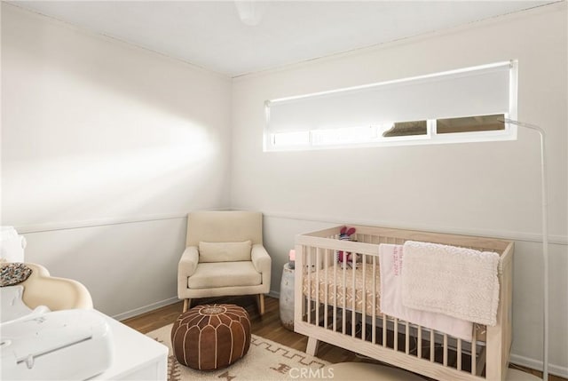 bedroom with wood-type flooring and a nursery area