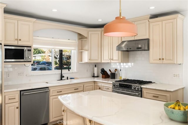 kitchen with stainless steel appliances, backsplash, hanging light fixtures, cream cabinets, and sink