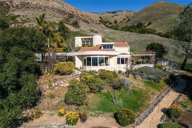 back of property featuring a mountain view and solar panels