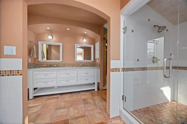 bathroom with lofted ceiling, vanity, walk in shower, tasteful backsplash, and tile patterned floors