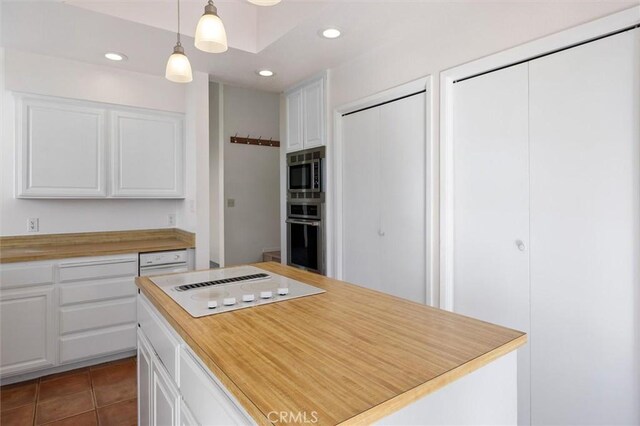 kitchen with hanging light fixtures, white cabinets, stainless steel microwave, and oven