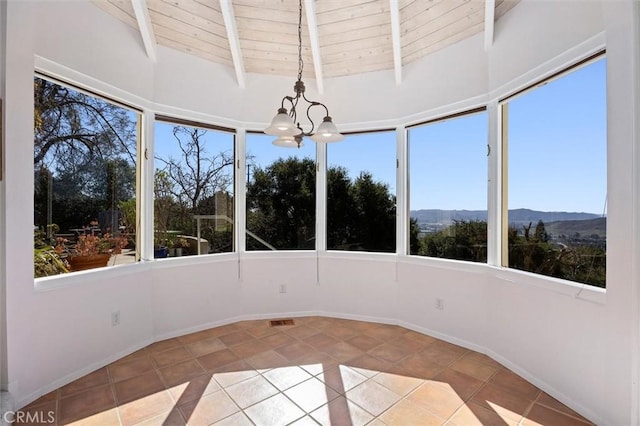 unfurnished sunroom featuring wood ceiling, a mountain view, plenty of natural light, and a notable chandelier