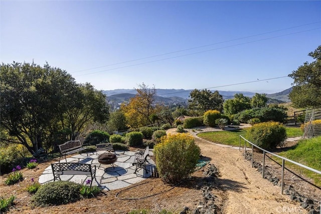 view of yard with a mountain view, a patio area, and a fire pit