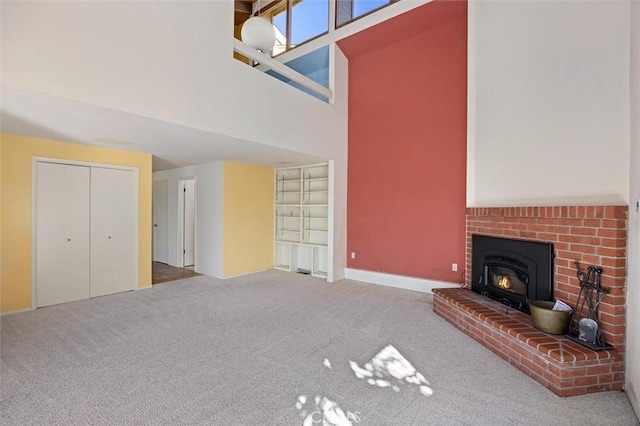 unfurnished living room with a fireplace, a high ceiling, and carpet flooring