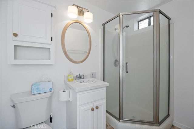 bathroom featuring a shower with shower door, toilet, and vanity