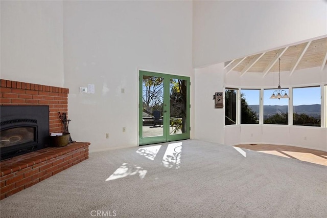 unfurnished living room with an inviting chandelier, wood ceiling, a mountain view, carpet floors, and beam ceiling