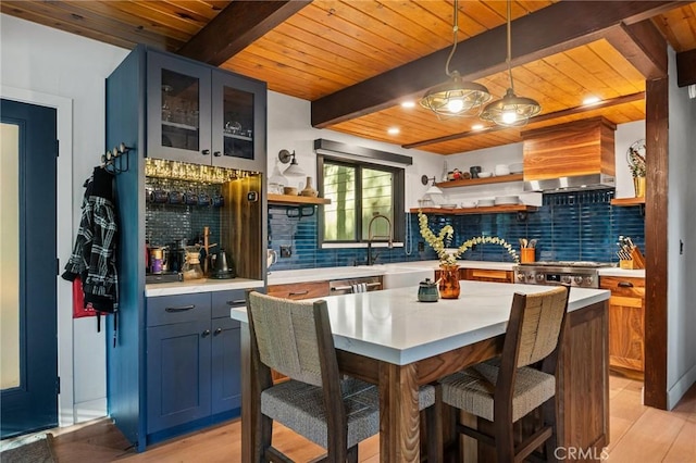 kitchen with light hardwood / wood-style floors, blue cabinetry, pendant lighting, and tasteful backsplash