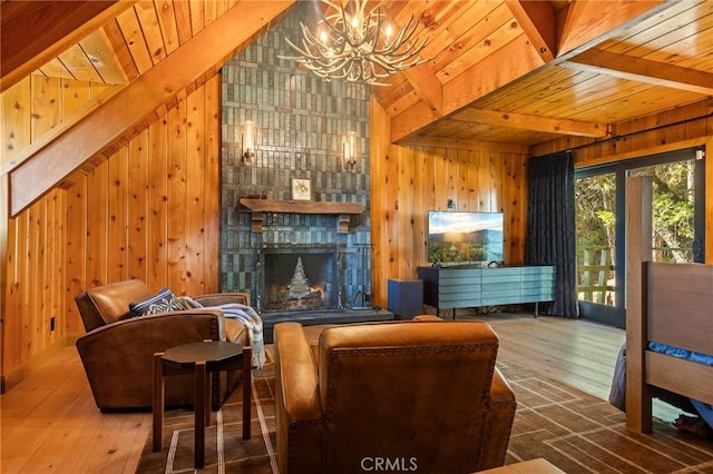 interior space with a stone fireplace, wood walls, a chandelier, lofted ceiling with beams, and hardwood / wood-style flooring