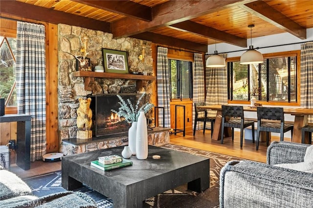 living room featuring wooden ceiling, wood-type flooring, beam ceiling, and a stone fireplace