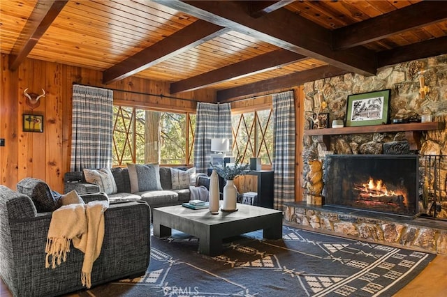 living room with beam ceiling, a stone fireplace, and wooden walls