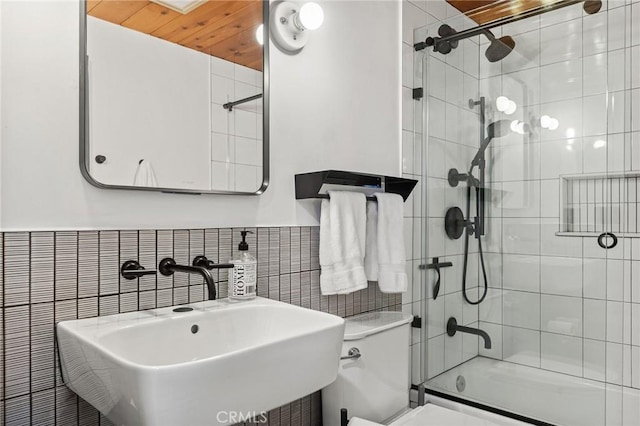 full bathroom featuring toilet, tile walls, sink, and combined bath / shower with glass door