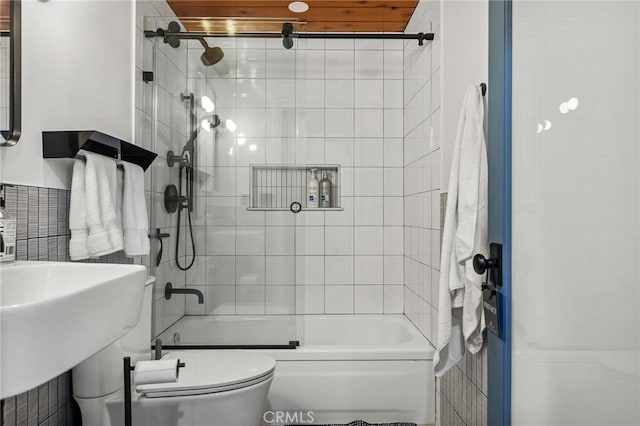 bathroom with toilet, wooden ceiling, and tiled shower / bath