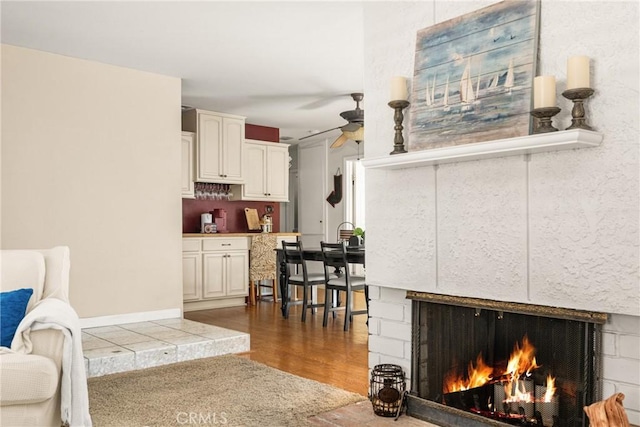 living room featuring a tiled fireplace, dark hardwood / wood-style floors, and ceiling fan