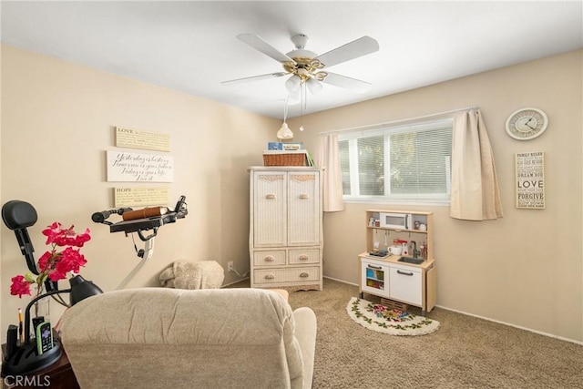 sitting room with ceiling fan and carpet flooring