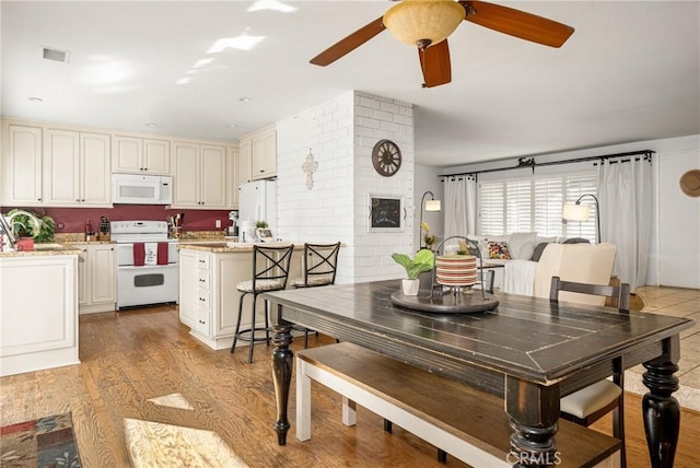 dining space with ceiling fan and light hardwood / wood-style flooring