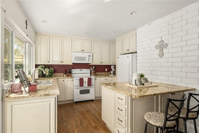 kitchen featuring a kitchen breakfast bar, light stone countertops, and white appliances