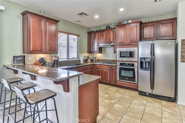 kitchen with sink, a breakfast bar area, stainless steel appliances, and dark stone counters