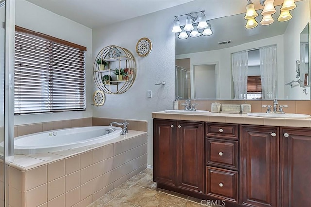 bathroom featuring a relaxing tiled tub and vanity