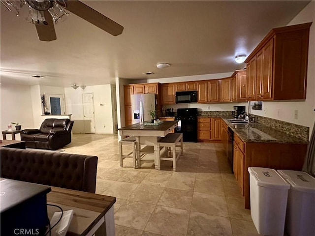 kitchen featuring ceiling fan, sink, dark stone counters, and black appliances