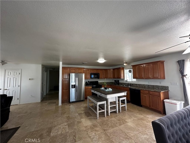 kitchen featuring sink, black appliances, a textured ceiling, and a kitchen island