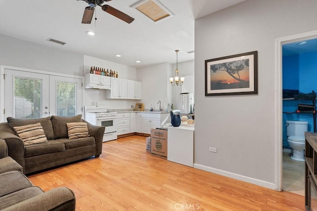 living room with french doors, sink, ceiling fan with notable chandelier, and light hardwood / wood-style flooring