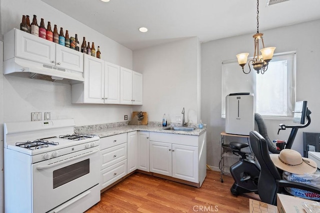 kitchen featuring an inviting chandelier, pendant lighting, white gas range, white cabinets, and sink