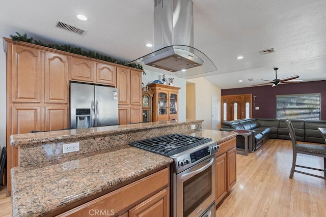 kitchen with ceiling fan, light hardwood / wood-style floors, island exhaust hood, stainless steel appliances, and light stone counters