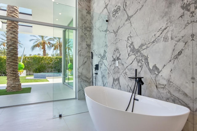 bathroom featuring a bathing tub, tile walls, and expansive windows