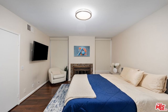 bedroom featuring a fireplace and dark hardwood / wood-style floors