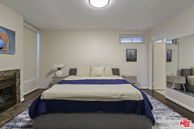 bedroom with dark wood-type flooring and a fireplace