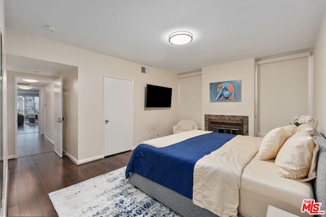 bedroom featuring a high end fireplace and dark hardwood / wood-style flooring