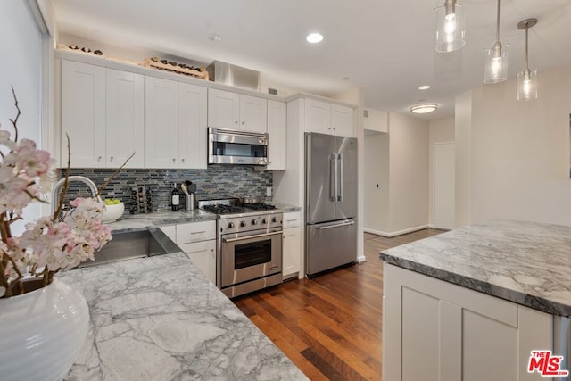 kitchen with white cabinetry, hanging light fixtures, premium appliances, dark wood-type flooring, and light stone counters