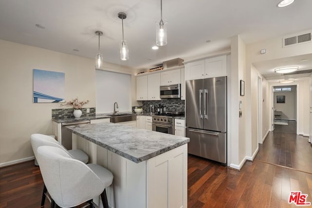 kitchen with pendant lighting, sink, white cabinetry, dark wood-type flooring, and high quality appliances