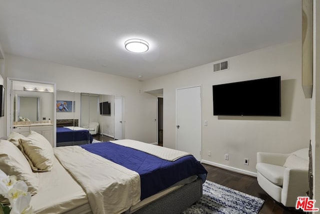 bedroom featuring dark wood-type flooring and ensuite bathroom