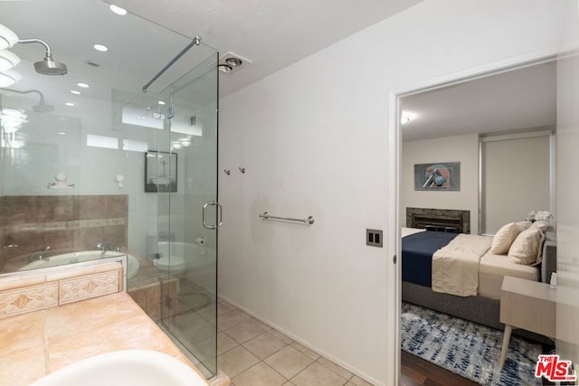 bathroom with tile patterned floors, a shower with door, and a fireplace