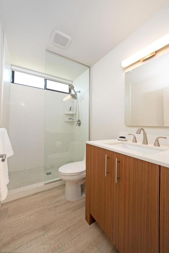 bathroom featuring toilet, wood-type flooring, walk in shower, and vanity