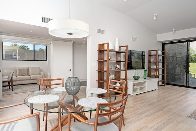 dining room with vaulted ceiling and light wood-type flooring