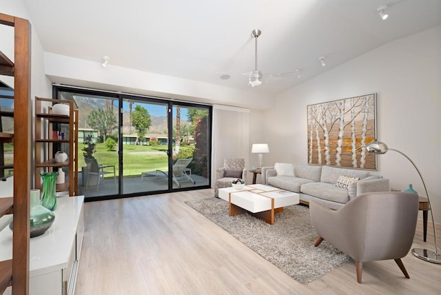 living room with light wood-type flooring, ceiling fan, and lofted ceiling