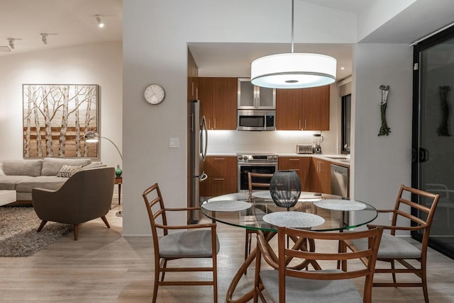 dining room featuring lofted ceiling and light hardwood / wood-style flooring