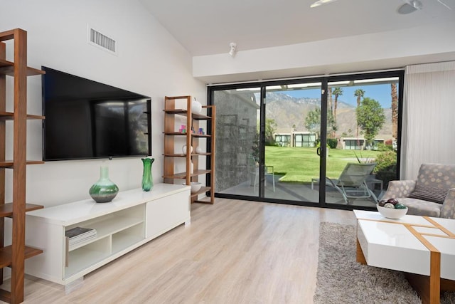 living room featuring lofted ceiling, a wealth of natural light, and light hardwood / wood-style floors