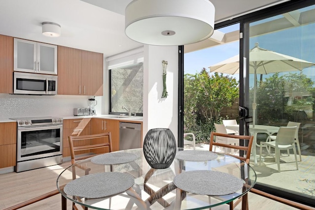 kitchen with a wealth of natural light, appliances with stainless steel finishes, light hardwood / wood-style flooring, and sink