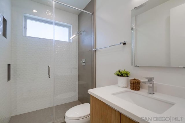 bathroom featuring toilet, vanity, and walk in shower