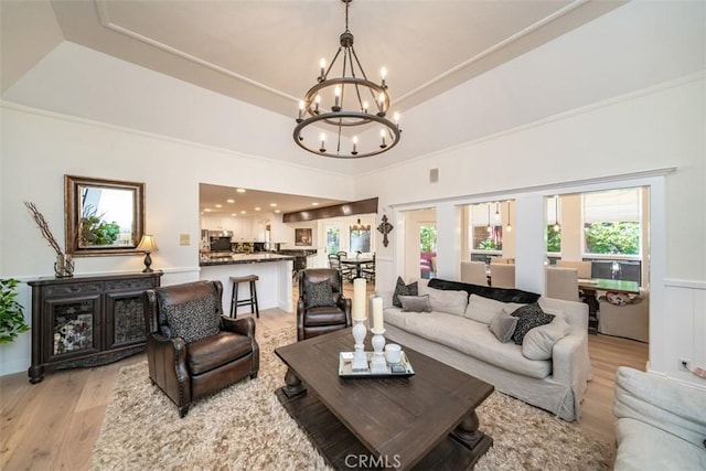 living room featuring a tray ceiling, a chandelier, and light wood-type flooring